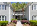 Inviting condo entrance with lush landscaping and tropical palm trees framing the walkway at 106 Pickering Ln, Charleston, SC 29414