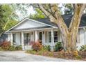 Charming one-story home with a covered front porch and beautiful landscaping under a large tree at 1106 Meadowcroft Ln, Mount Pleasant, SC 29464