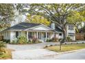 Charming one-story home with a well-manicured lawn and beautiful landscaping under a large tree at 1106 Meadowcroft Ln, Mount Pleasant, SC 29464