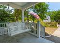Inviting front porch with a classic porch swing and the American flag, offering a relaxing outdoor space at 115 Peachtree St, Charleston, SC 29403