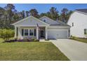 Charming single-story home with a manicured lawn, an attached garage, and an American flag on the front porch at 117 Camellia Bloom Dr, Moncks Corner, SC 29461