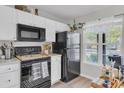 Compact kitchen featuring white cabinets and modern black appliances next to a window at 122 Brockman Way, Goose Creek, SC 29445