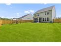 Spacious backyard with a large grassy area, wooden fence, screen porch, and play area at 1728 Refuge Dr, Ladson, SC 29456