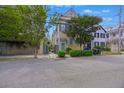 Charming two-story home with a light yellow exterior, teal shutters and door, and mature trees at 197 Coming St, Charleston, SC 29403