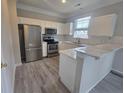 Modern kitchen features white cabinets, stainless steel appliances, and a marble countertop breakfast bar at 209 Killarney Trl, Moncks Corner, SC 29461