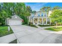 Beautiful two-story home with a detached garage, long driveway, and inviting front porch with chairs and landscaping at 2668 Private Lefler Dr, Johns Island, SC 29455