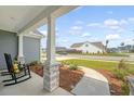 Relaxing front porch with stone pillars and rocking chairs overlooking a quiet, residential street at 317 Fiddleback Dr, Summerville, SC 29486