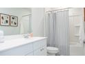 Bright bathroom features a white vanity, framed mirror, framed art and a tub with a stylish striped curtain at 339 Pine Crest View Dr, Summerville, SC 29486