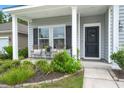 Inviting front porch with seating area, landscaping, and a black door with a wreath at 3438 Great Egret Dr, Johns Island, SC 29455
