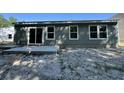 Back exterior features gray siding, windows, and a concrete patio in a sandy lot at 5031 Scow Ct, Summerville, SC 29485