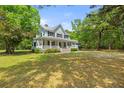 Two-story home featuring classic architecture with a spacious front yard and mature trees in a serene setting at 5950 Kelseys Mill Rd, Ravenel, SC 29470