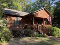 Inviting log cabin featuring a quaint front porch, well-maintained landscaping, and an American flag display at 1020 Welles Ln, Walterboro, SC 29488