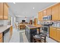 A well-equipped kitchen features stainless steel appliances, center island, wood cabinets, and access to the living area at 1218 Cosmos Rd, Summerville, SC 29483