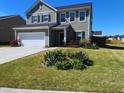 Inviting home with vibrant landscaping, manicured lawn, and a charming flower bed enhancing its curb appeal at 167 Cypress Plantation Rd, Moncks Corner, SC 29461