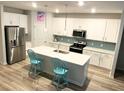 Modern kitchen featuring white cabinets, an island with bar seating, stainless steel appliances, and stylish pendant lighting at 167 Cypress Plantation Rd, Moncks Corner, SC 29461