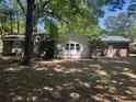 View of the back of the home and the backyard which has mature trees and a small shed in the distance at 1866 Ashley Hall Rd, Charleston, SC 29407