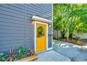 Close up of home's stylish yellow front door with modern lighting and beautiful landscaping at 2130 Weaver St, Charleston, SC 29403