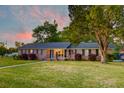 Traditional brick home with a well-manicured lawn, symmetrical windows, and black shutters at dusk at 2506 Birkenhead Dr, Charleston, SC 29414