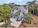 Coastal style home with a circular driveway, lush green trees, and natural outdoor space at 3635 Pompano Ct, Seabrook Island, SC 29455