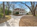 Two-story home featuring a classic wrap-around porch and a curved driveway, surrounded by mature trees and greenery at 49 Crosscreek Dr, Charleston, SC 29412