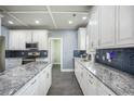 Modern kitchen with white cabinets, grey tile flooring, stainless appliances, and attractive backsplash at 603 Curing Ct, Moncks Corner, SC 29461