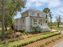 Beautiful two-story home with dormer windows, inviting porch, and lush landscaping with a blue sky backdrop at 1006 Basin Ln, Johns Island, SC 29455