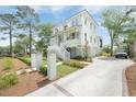 Charming white home featuring a welcoming front porch, lush landscaping, and a concrete driveway leading to a garage at 1006 Basin Ln, Johns Island, SC 29455