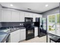 Well-lit kitchen featuring white cabinets and modern black appliances at 104 Buchanan Cir, Goose Creek, SC 29445