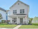Charming two-story white home featuring a cozy front porch with seating and a well-manicured lawn at 107 Amaranth Ave, Summerville, SC 29483