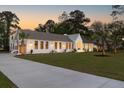 Well-lit single-story home with a long driveway, manicured lawn, and crisp white painted brick exterior at 1183 Farm Quarter Rd, Mount Pleasant, SC 29464