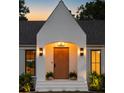 Home's front entrance showcasing a modern wood door, elegant sconces, and well manicured plants at 1183 Farm Quarter Rd, Mount Pleasant, SC 29464