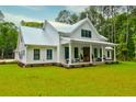 Charming farmhouse featuring a metal roof, covered front porch, and lush green lawn at 1183 Guerins Bridge Rd, Awendaw, SC 29429