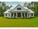 Inviting two-story farmhouse with a metal roof and a covered front porch, with verdant green front lawn at 1183 Guerins Bridge Rd, Awendaw, SC 29429