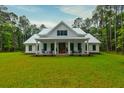 Beautiful two-story farmhouse with a metal roof and a covered front porch, set on a verdant lawn at 1183 Guerins Bridge Rd, Awendaw, SC 29429