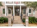 A charming brick home's entry way, detailed with stately columns, landscaped plantings, and clear numbering at 185 River Green Pl, Daniel Island, SC 29492