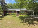 Quaint brick home with manicured greenery, driveway and covered carport surrounded by mature trees at 2438 Two Oaks Dr, Charleston, SC 29414