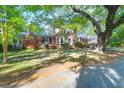 Beautiful red brick home nestled among mature trees showcases professional landscaping and charming architectural details at 41 Berkeley Rd, Charleston, SC 29407