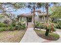 Attractive exterior view of home featuring mature landscaping and stairs to porch at 418 Snowy Egret Ln, Kiawah Island, SC 29455