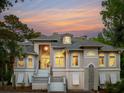 Elegant home with symmetrical design, well-lit entry, and manicured front yard against a colorful sky at 4952 Steeplechase Ln, Hollywood, SC 29449