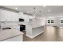 Bright, open kitchen features stainless appliances, island, pendant lights, and hardwood floors at 5114 Double Eagle Loop, Summerville, SC 29485