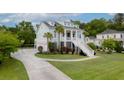 Charming light-blue two-story home with a welcoming staircase and columns, a long driveway, and lush landscaping at 1104 Beresford Run, Charleston, SC 29492