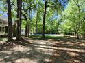 The backyard features a stone paver path leading towards a swimming pool surrounded by mature trees at 130 Delaney Cir, Summerville, SC 29485