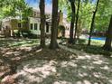 This backyard showcases a stone path leading to a pool and the home's rear exterior amidst lush trees at 130 Delaney Cir, Summerville, SC 29485