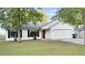 Inviting single-story home with a two-car garage, red front door, and attractive landscaping at 1341 Belle Grove Cir, Hanahan, SC 29410