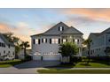 Charming two-story white home boasts a three-car garage, manicured lawn and classic design elements at 1562 Charming Nancy Rd, Charleston, SC 29412