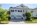 Charming two-story white home boasts a three-car garage, manicured lawn and classic design elements at 1562 Charming Nancy Rd, Charleston, SC 29412