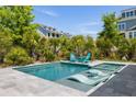Beautiful backyard pool with a tanning ledge, spa, turquoise Adirondack chairs, palm trees, and professional landscaping at 1659 Pierce St, Daniel Island, SC 29492