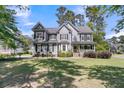 Charming two-story home featuring a welcoming front porch, manicured lawn, and classic architectural details at 1828 S James Gregarie Rd, Mount Pleasant, SC 29466