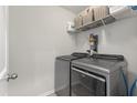 Well-equipped laundry room with modern gray washer and dryer and storage shelves for convenience at 210 Witch Hazel St, Summerville, SC 29486