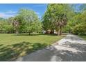 Spacious green lawn with mature trees and a concrete driveway leading to a charming residential home at 3756 Colonel Vanderhorst Cir, Mount Pleasant, SC 29466